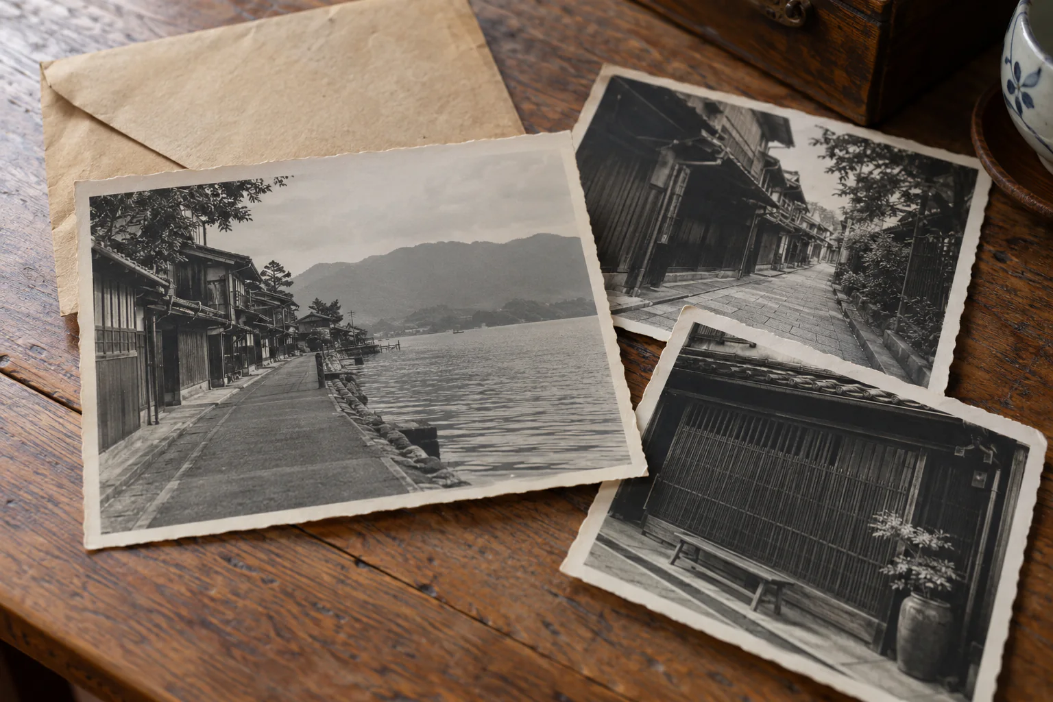古い無人の町並み写真と当時の封筒を並べた机