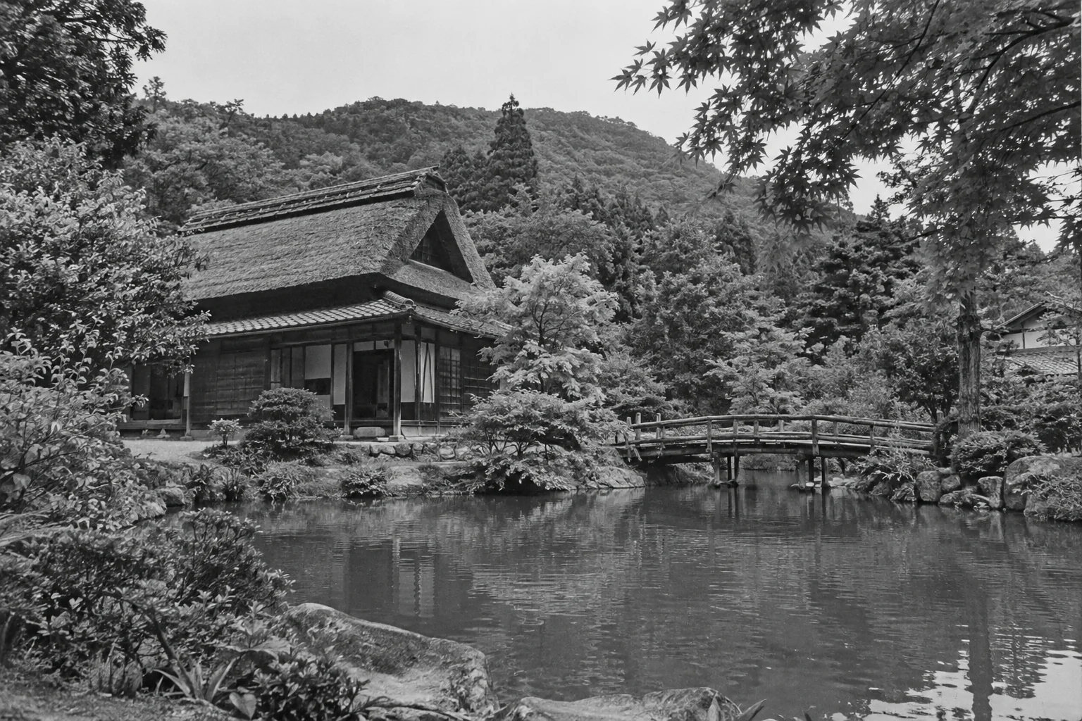 池と橋、茅葺きの家を写したモノクロの風景